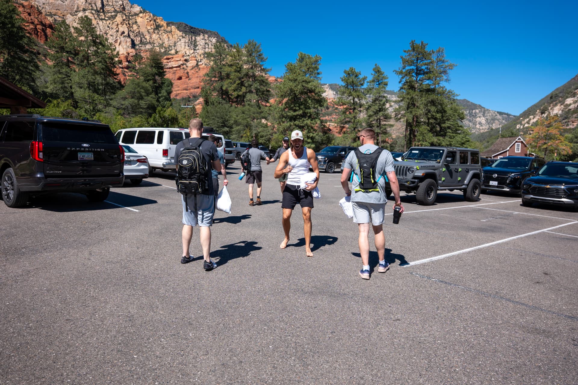 Men with backpacks gathering beneath red rock mountains
