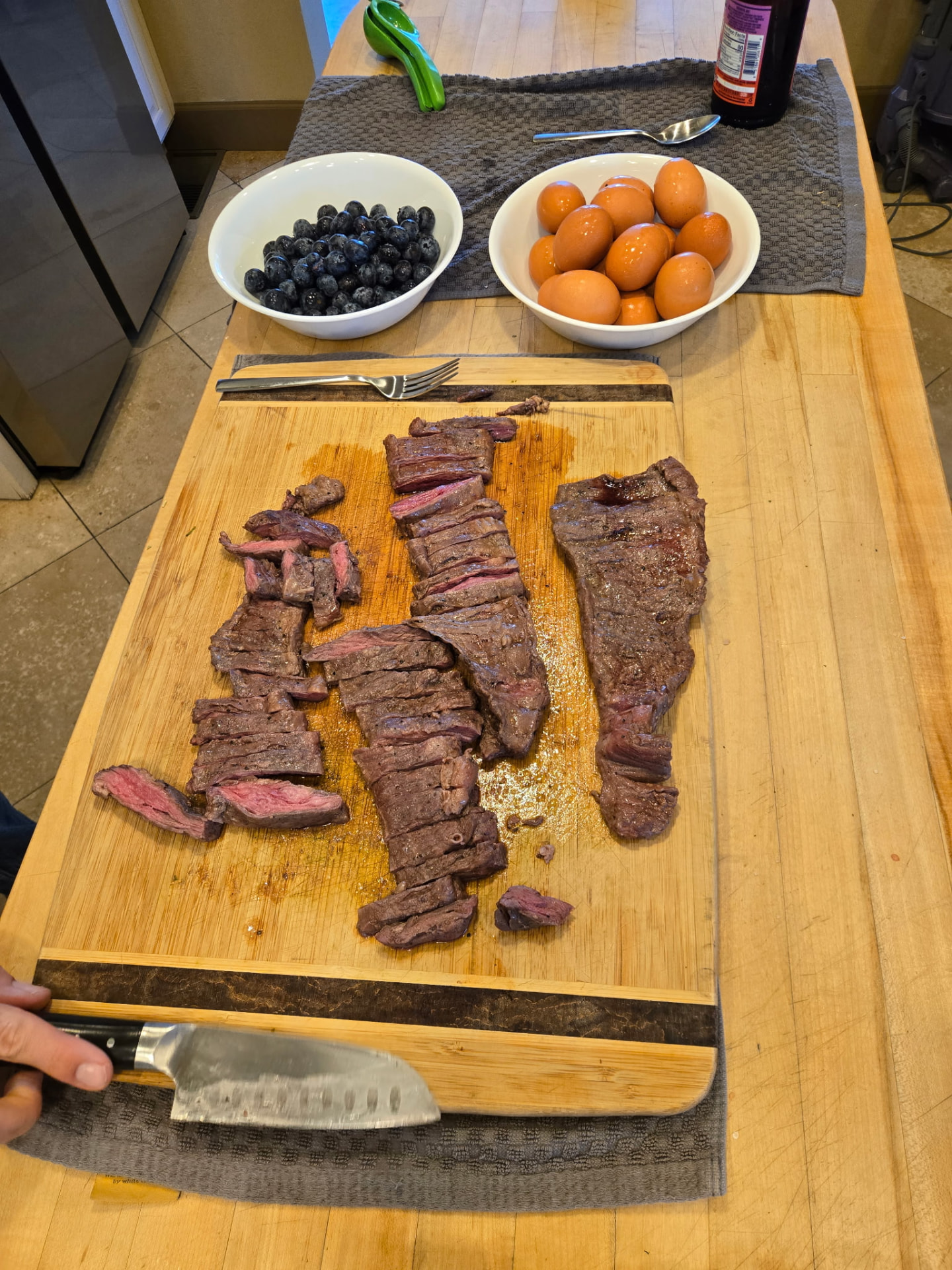 Freshly sliced steak, eggs, and blueberries prepared on a wooden kitchen counter